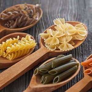Verschiedene glutenfreie italienische Pastaarten auf Holzlöffeln.